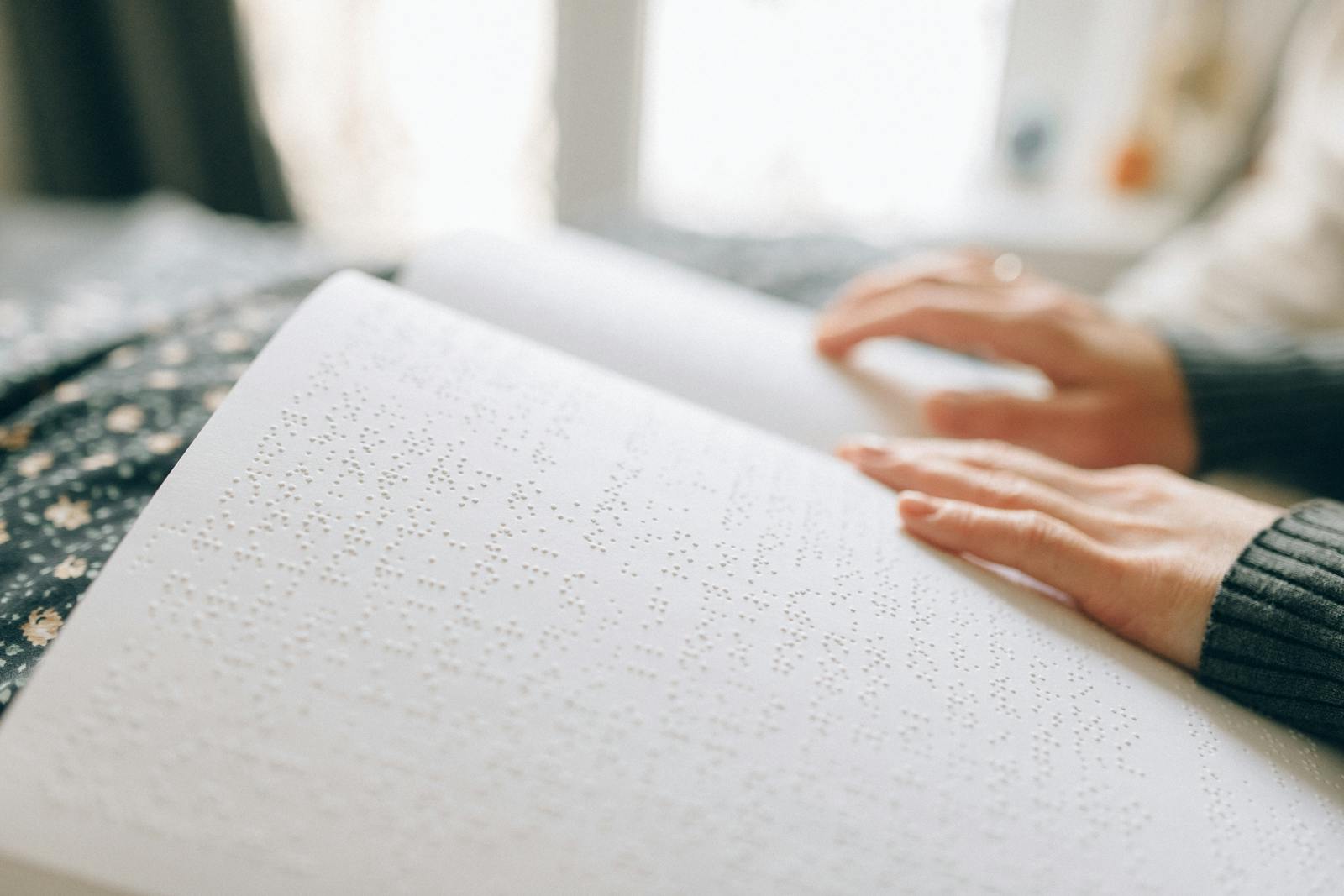 Close-up of hands reading a braille book, emphasizing tactile learning.
